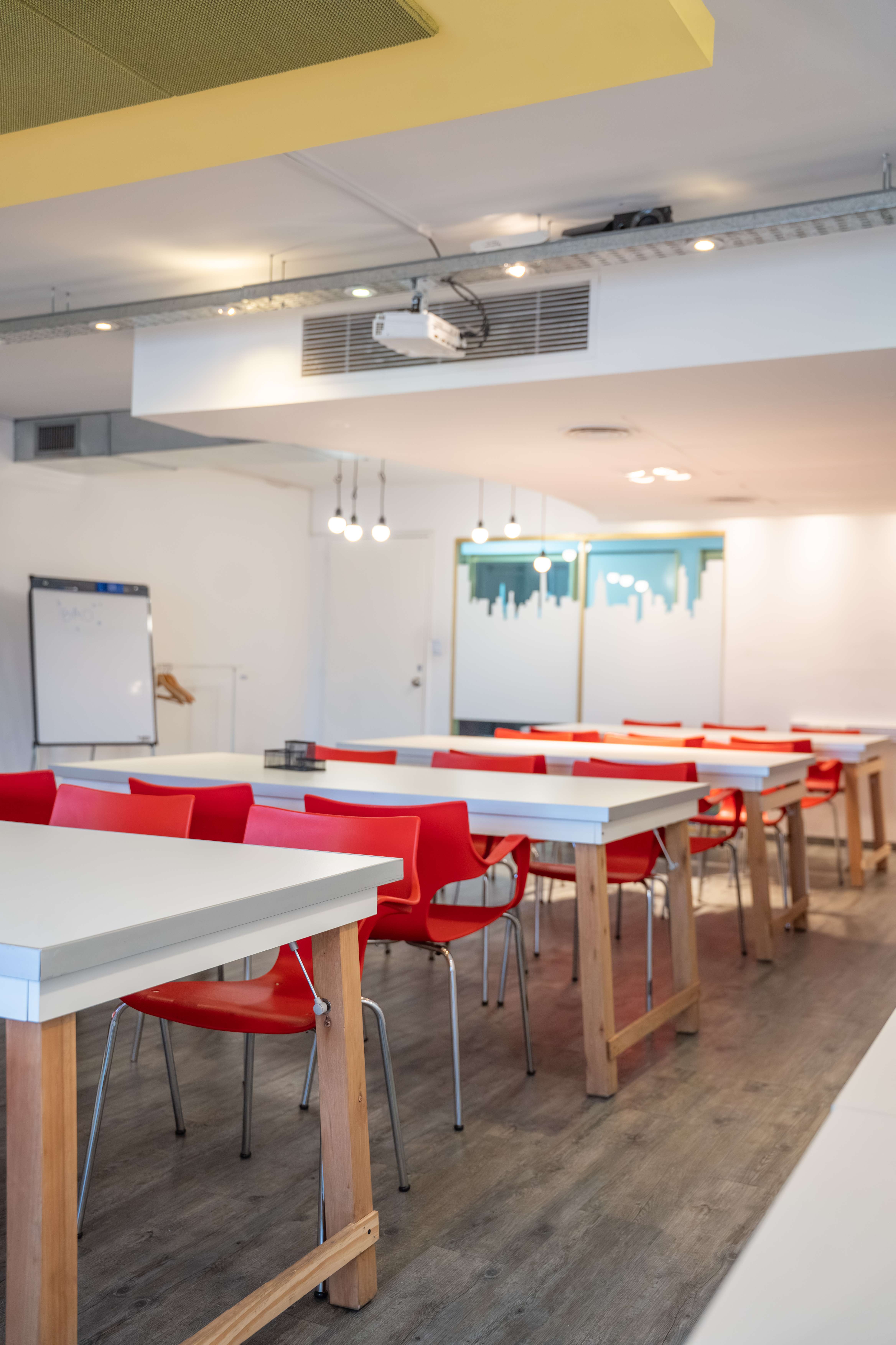 Salón de eventos de BAO Work Center con mesas blancas y sillas rojas en Av. Corrientes 1386